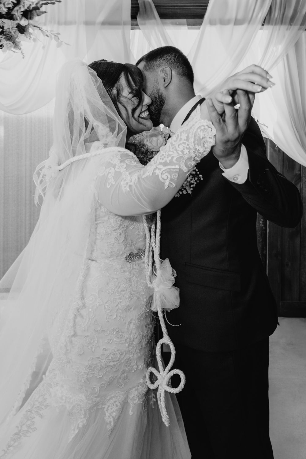 Black and white wedding photos showing intimate moments between a couple in formal attire with a white veil.