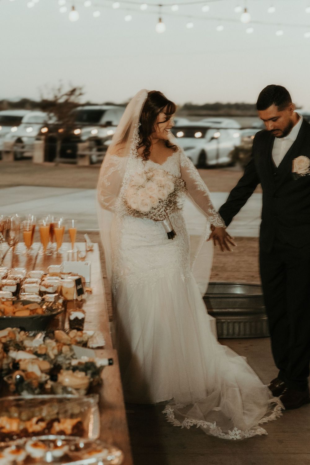 A romantic wedding reception setup with champagne glasses and string lights at sunset.
