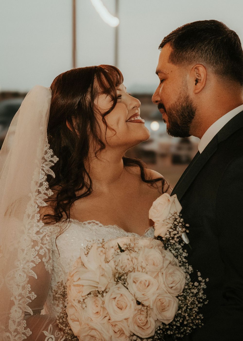 A romantic wedding couple shares tender kisses in a series of intimate portraits with soft pink roses and delicate veil details.