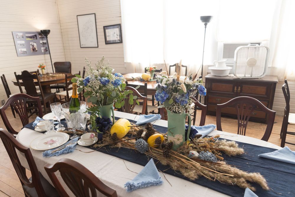 A rustic dining table set with blue linens, driftwood centerpiece, citrus fruits and natural decorations for a coastal theme.