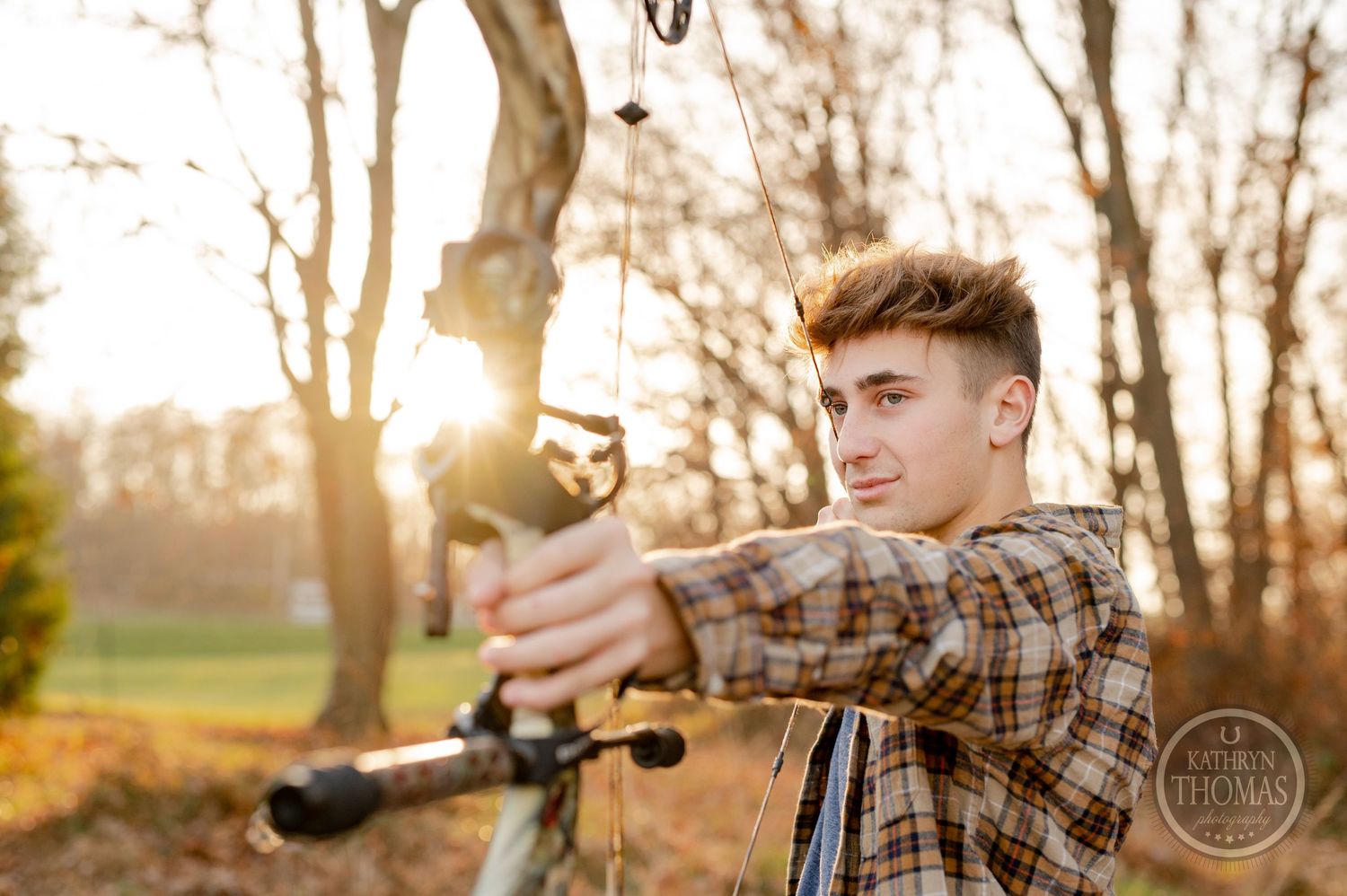 Archer practicing with compound bow against golden sunset in forest.
