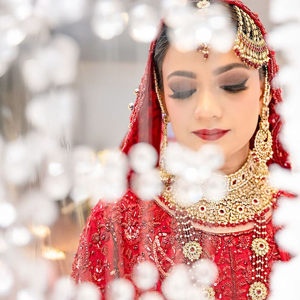 Close-up portrait of Indian bride in red lehenga with gold bridal jewelry and smoky eye makeup.