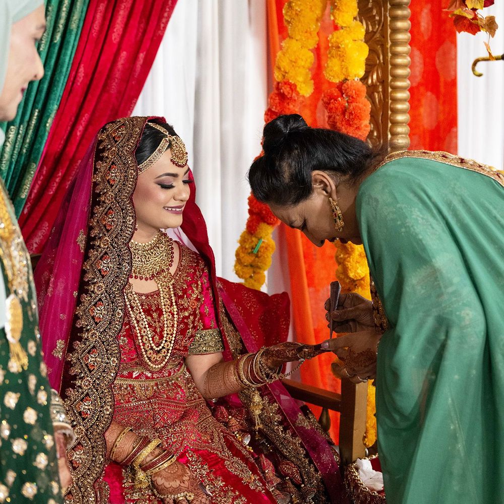 South Asian bride in red bridal lehenga receiving blessings during traditional wedding ceremony.