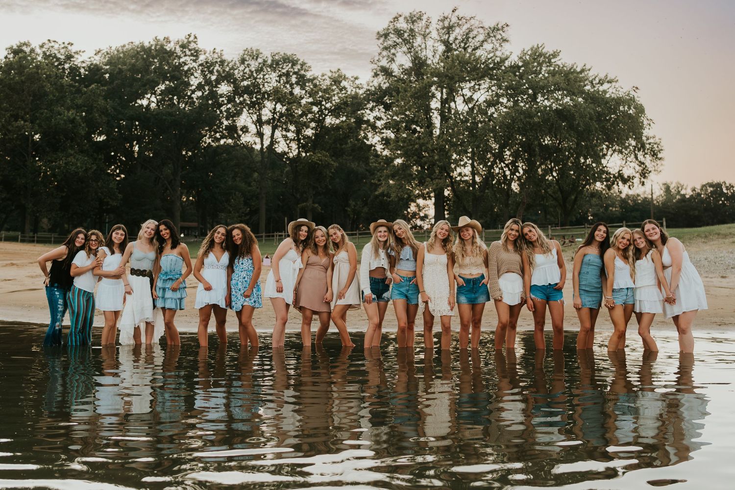 A group of friends at the beach at sunset. They are holding hands and all wearing cute dresses.