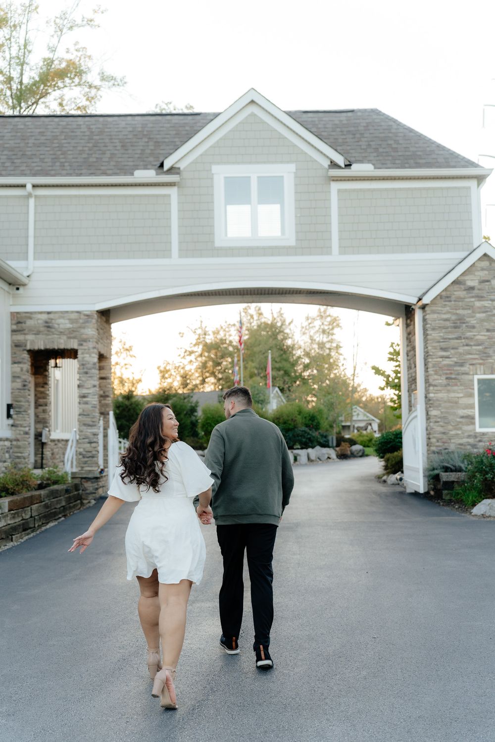 Couple walking away together under an elegant stone archway during golden hour.
