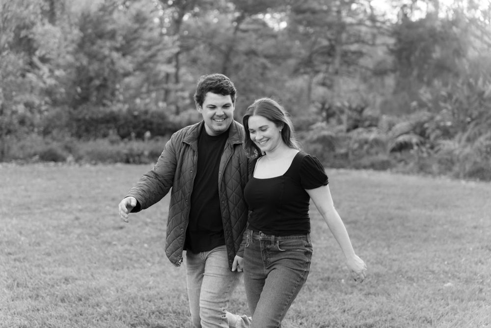 A black and white photo of a couple walking together in a park setting.