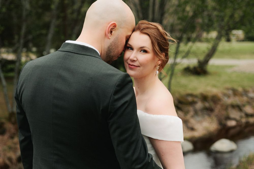 A bride and groom share an intimate moment together in a scenic outdoor garden setting.