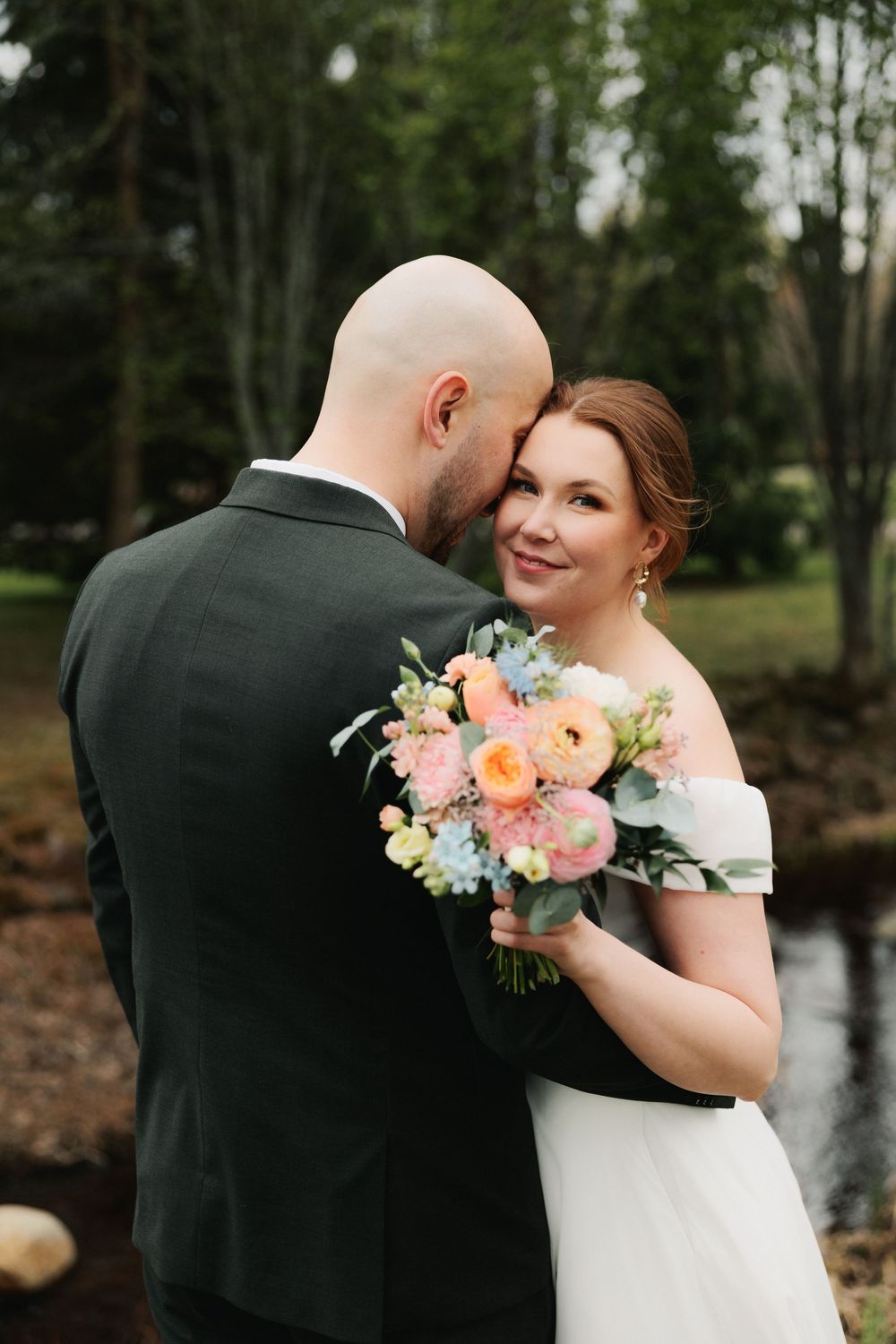 A romantic outdoor wedding photo series showing intimate moments between newlyweds with soft pink and blue floral bouquet.