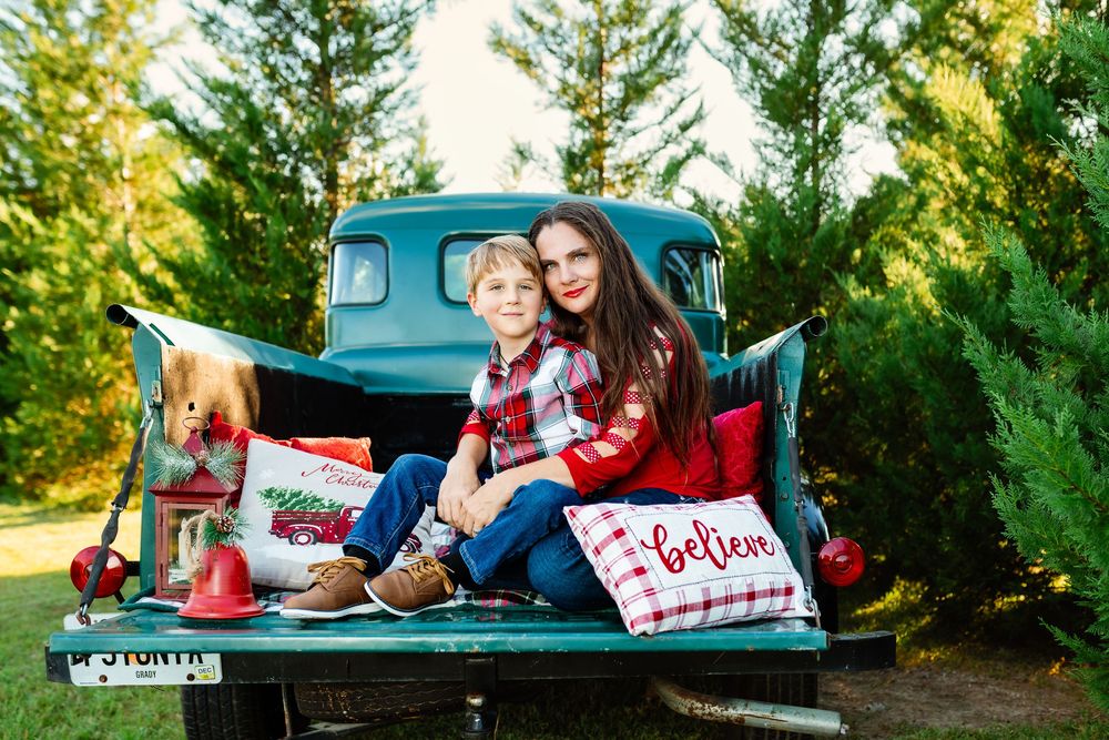 A vintage turquoise pickup truck parked among evergreen trees during a golden sunset photo session.