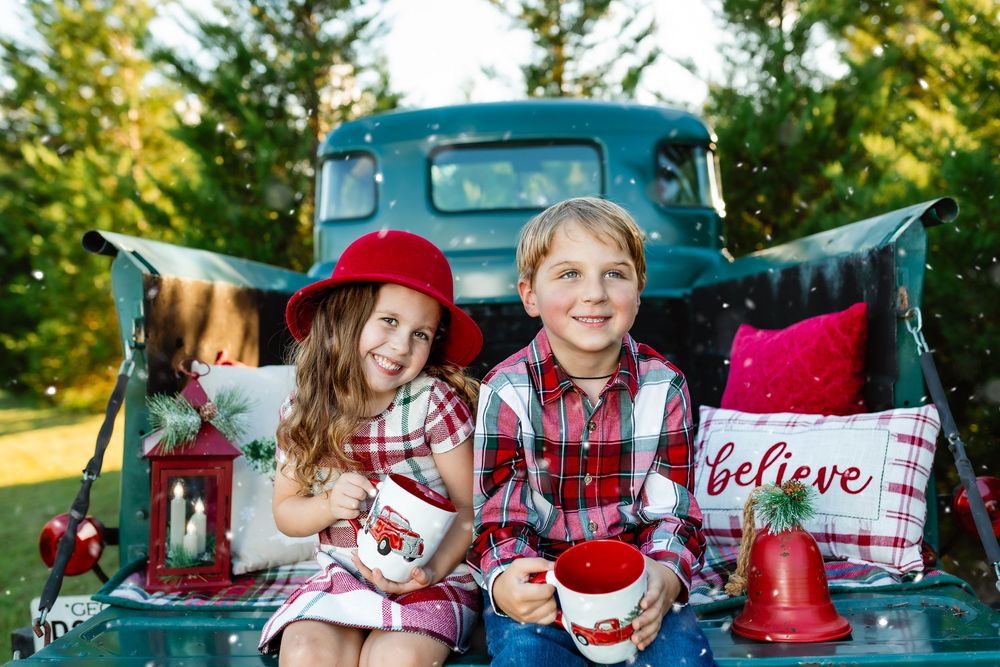 Holiday themed photo shoot with vintage teal truck and festive red decorations.