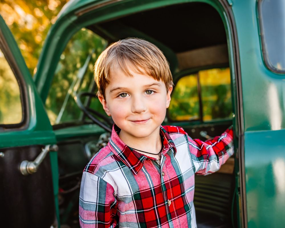 A vintage green pickup truck serves as a backdrop for outdoor portraits in warm golden lighting.