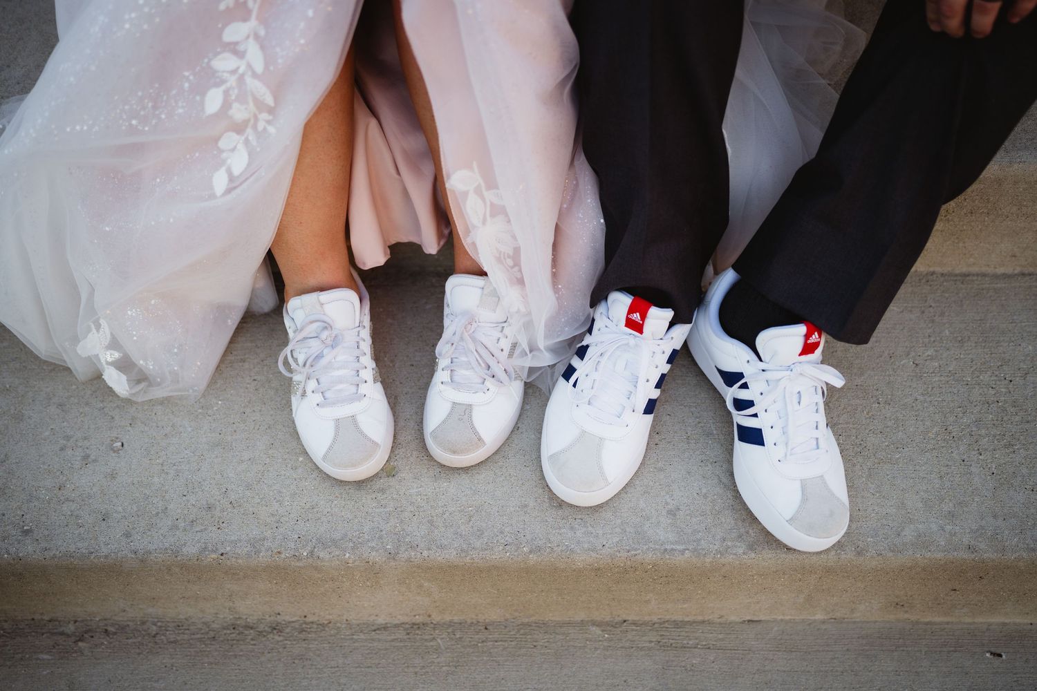 A row of people wearing formal attire showing their white sneakers and dress shoes while sitting together.