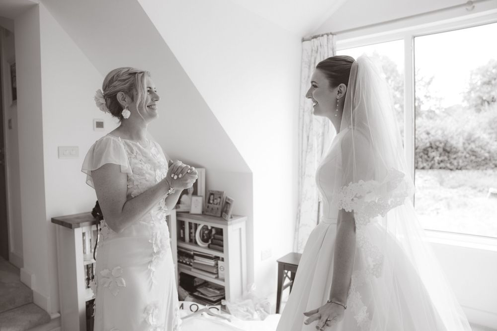 Emotional black and white moment between bride in veil and her mother during wedding morning preparations at home.