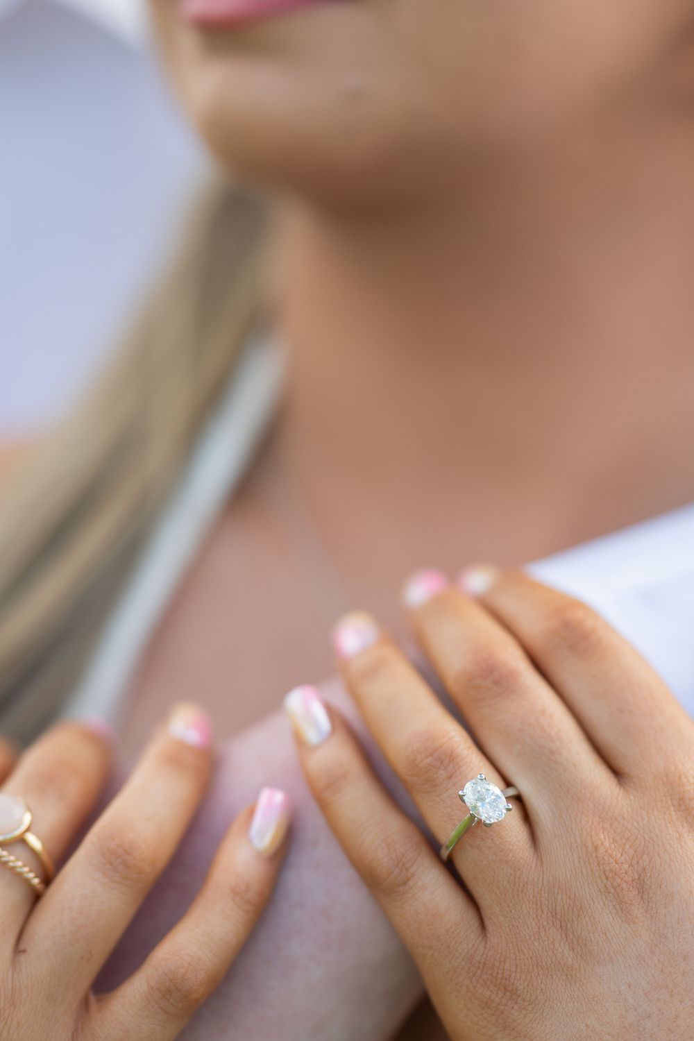 Close-up detail of hands showing off engagement rings with French manicured nails.