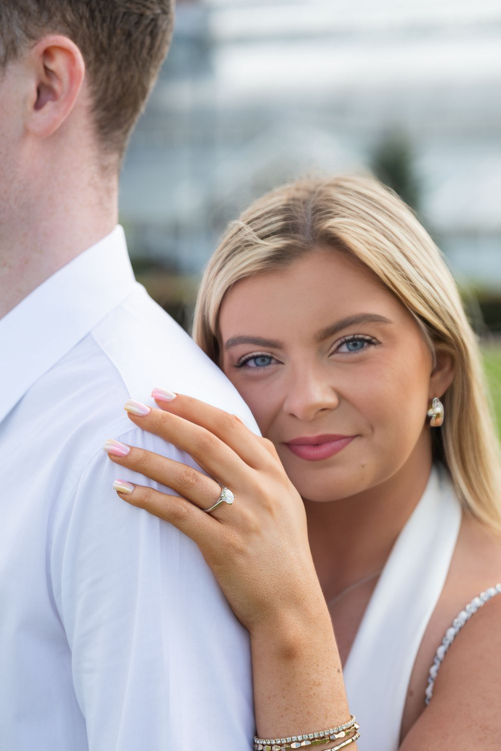 A tender moment captured in close-up showing a beautiful engagement ring and pearl earrings.