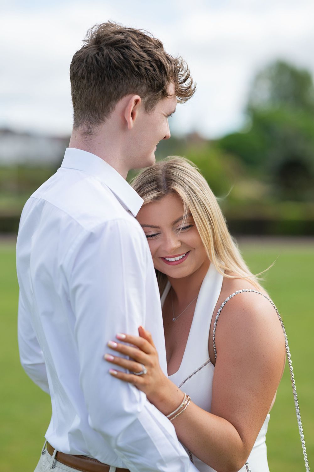 An intimate embrace captured outdoors on a sunny day with natural lighting.