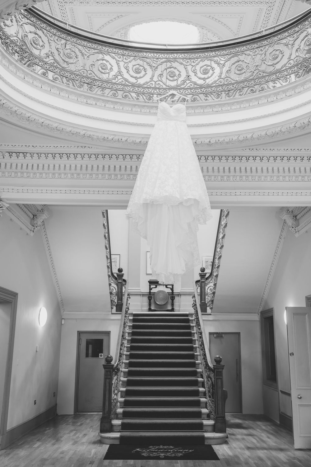 Elegant white interior hallway with ornate ceiling details and grand staircase in classical architectural style.