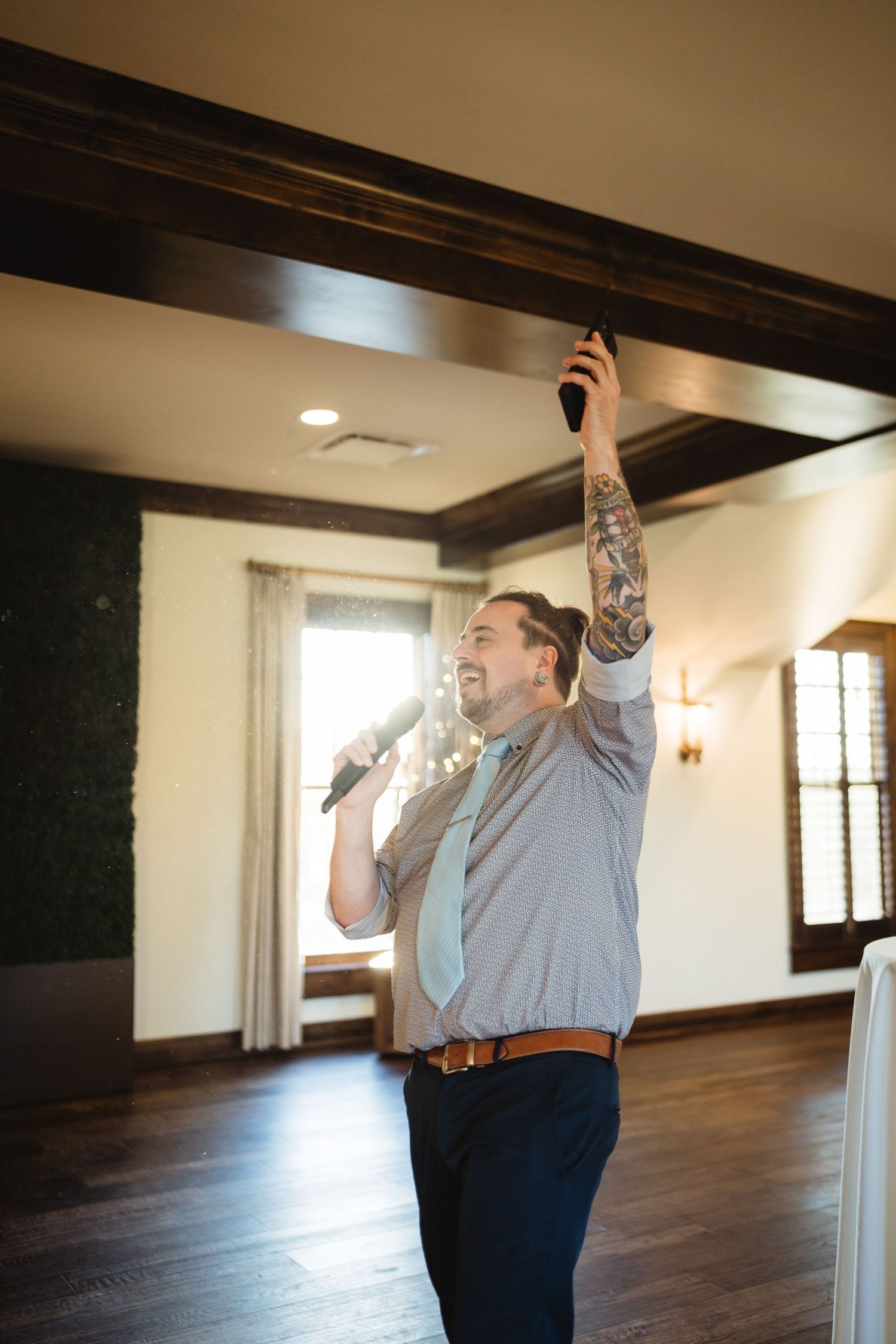 Person in jeans and light shirt celebrates joyfully in an empty room with wooden floors and white walls.