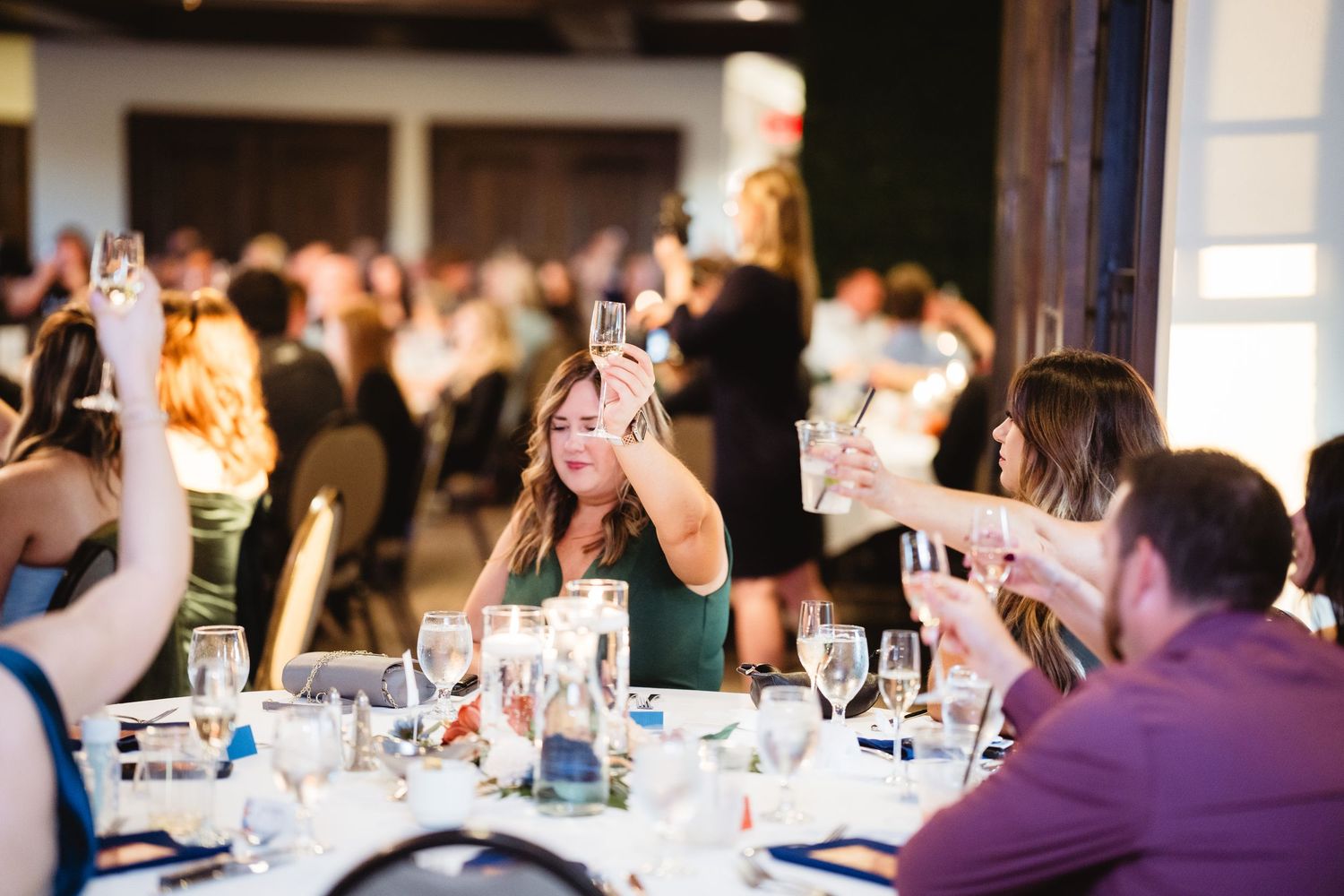A group of people seated at long tables during a wine tasting event with glasses and bottles visible.