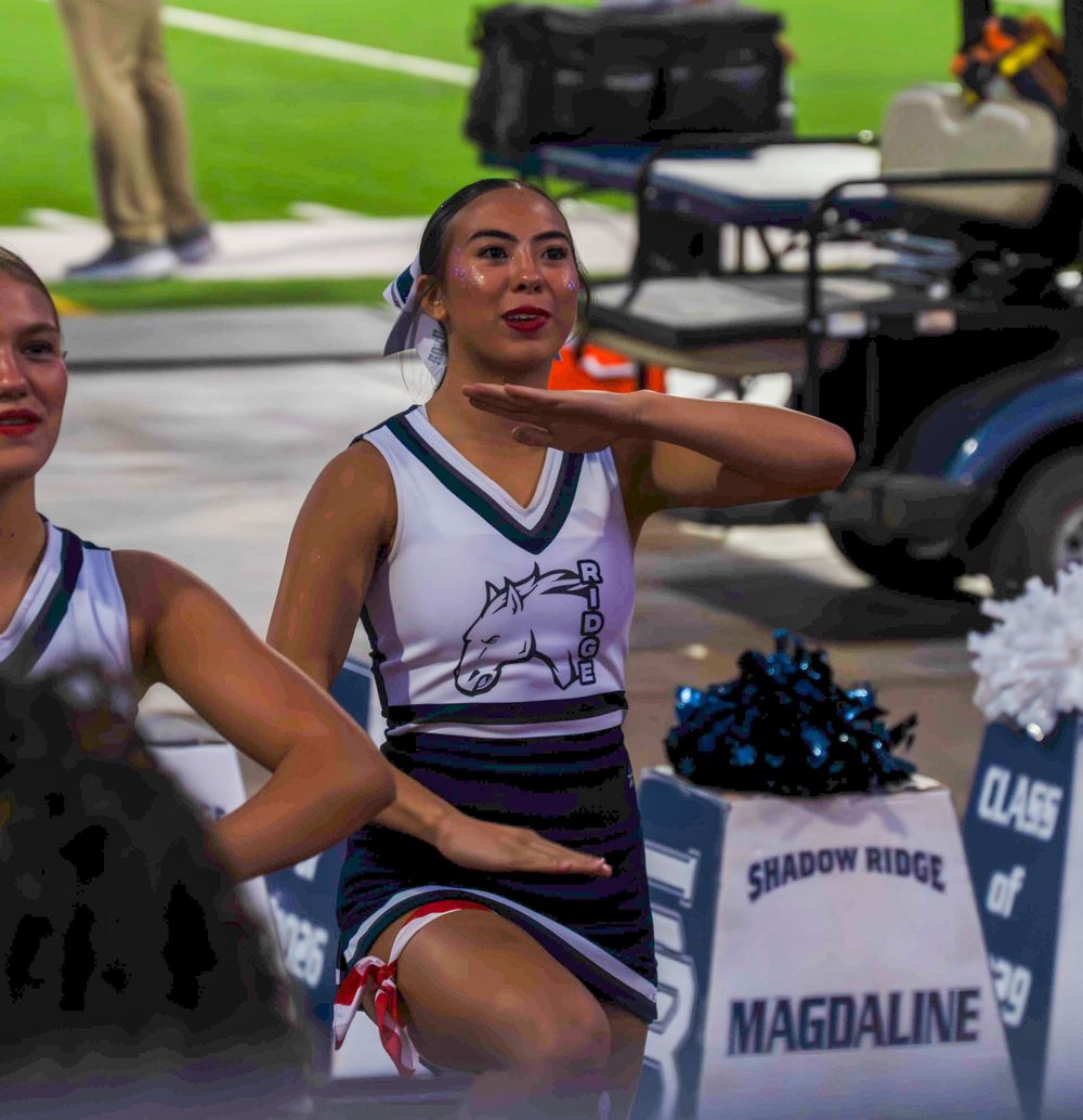 Shadow Ridge Mustangs cheerleader performing at a high school football game sideline.