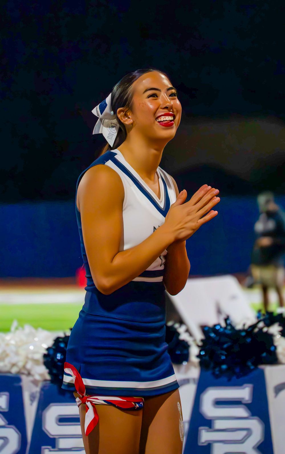 Shadow Ridge cheerleader clapping and smiling at a night high school football game.