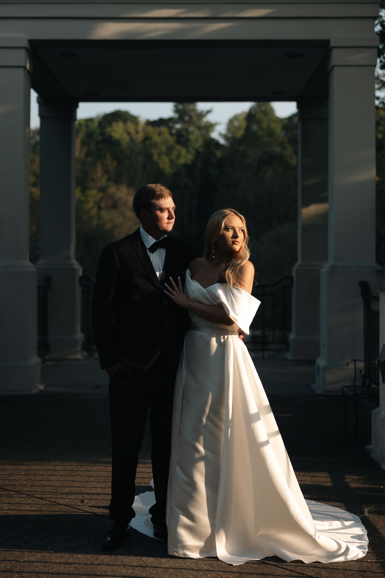 Dramatic wedding portraits taken under columned architecture with dark shadows.