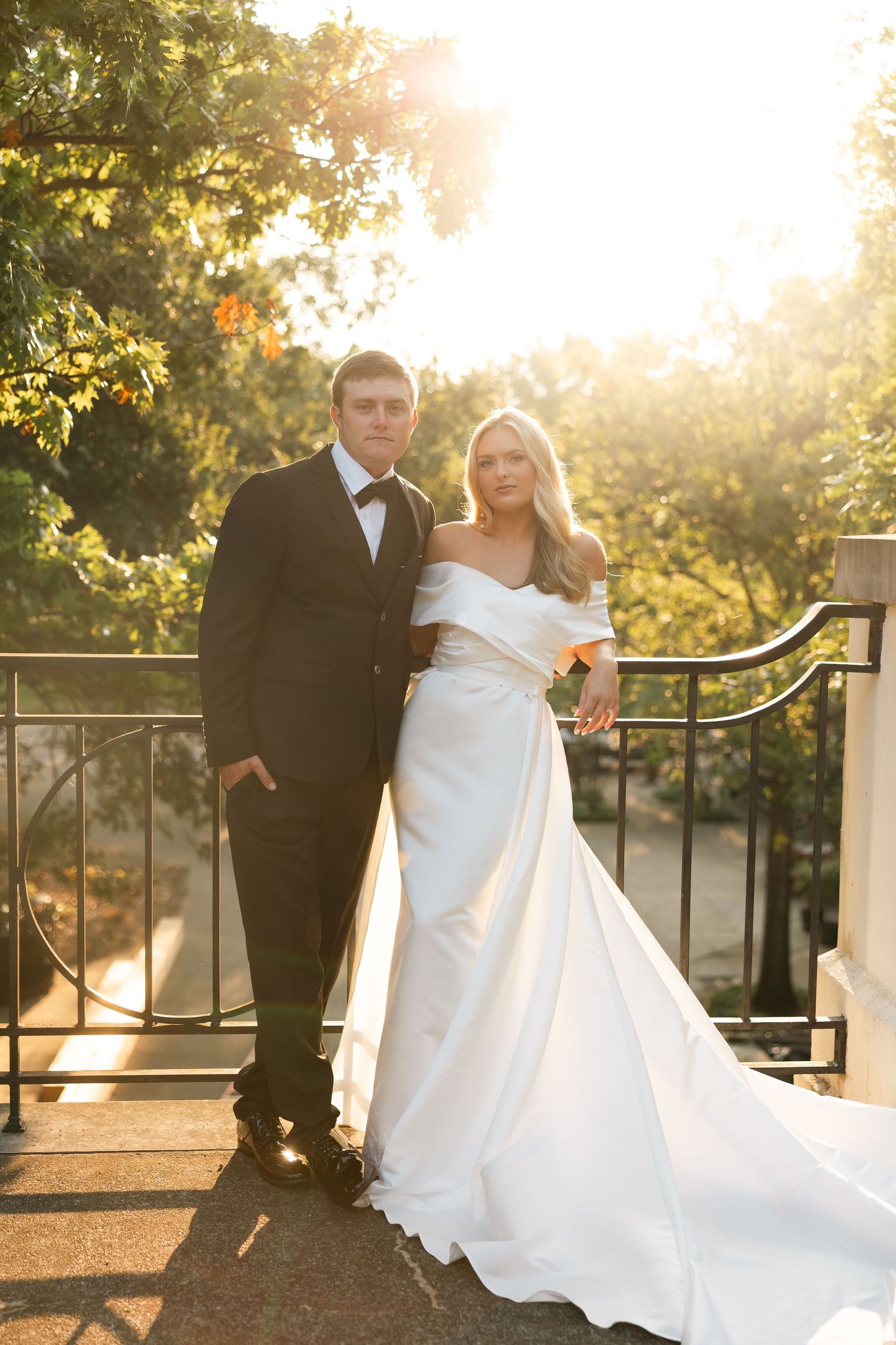 Sunset wedding portraits with couple against iron railing in golden light.