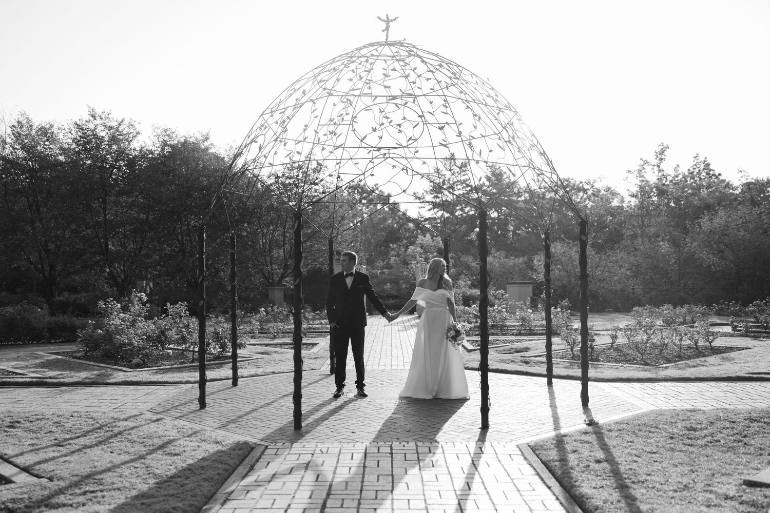 Silhouetted couple under domed gazebo structure in black and white photography.