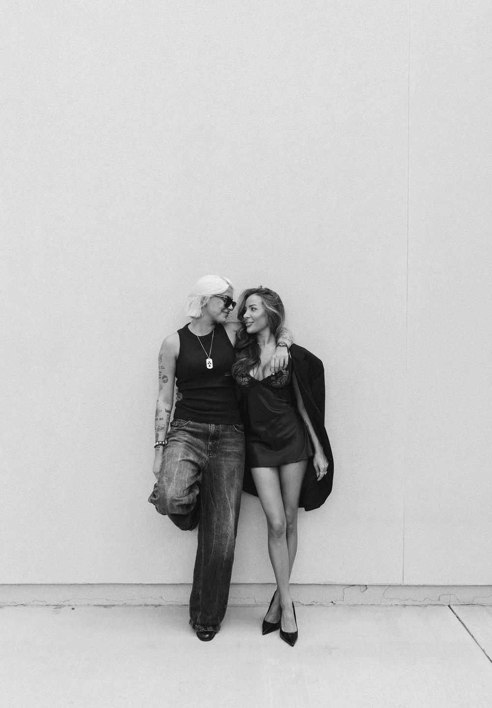 Minimalist black and white photo series of people sitting against a white wall.