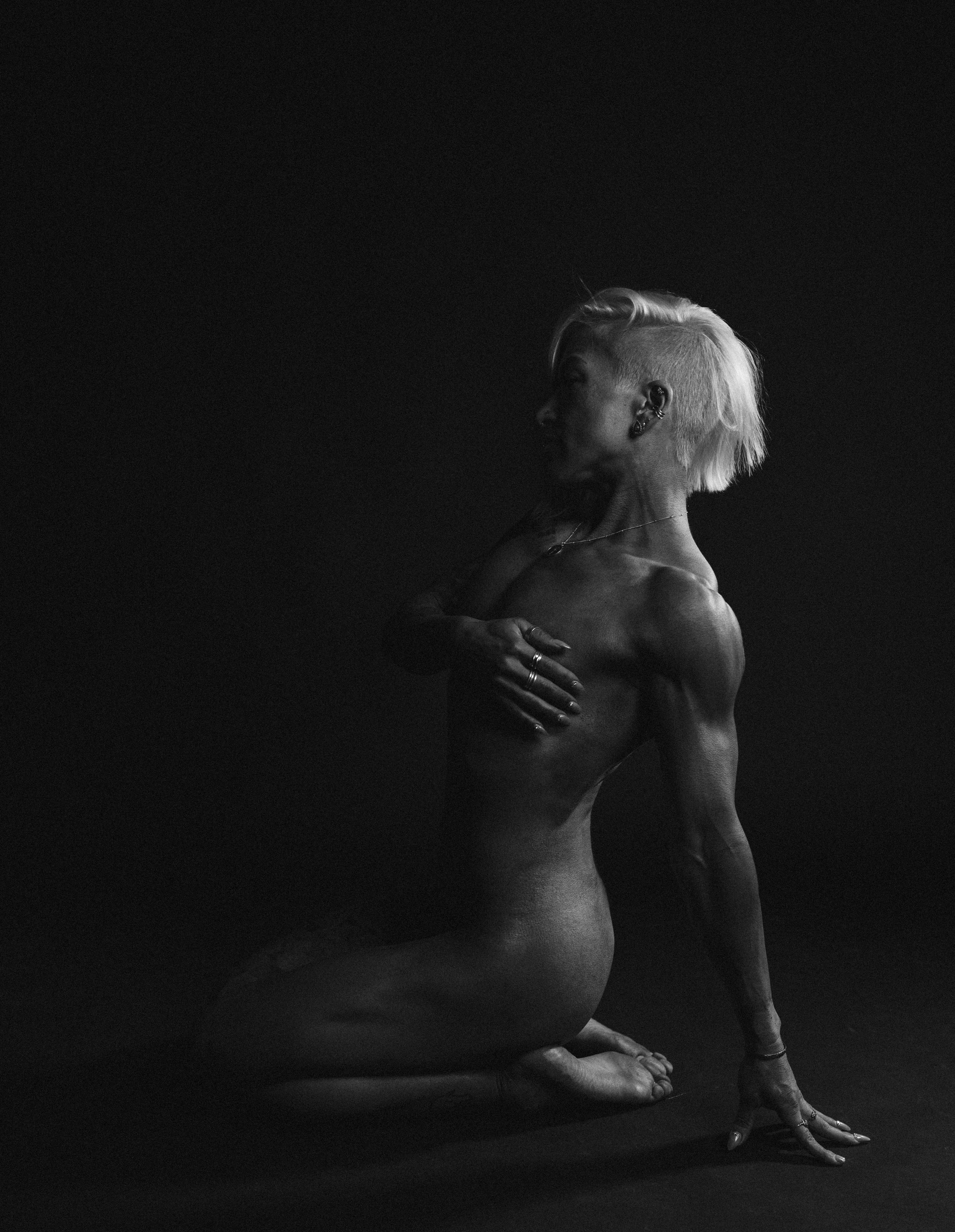 Artistic black and white nude figure study with dramatic lighting.