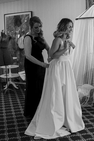 Wedding dress fitting session with attendants helping in black and white.
