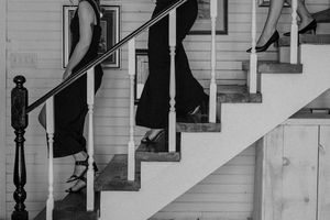 Wedding party descending white staircase in formal attire.