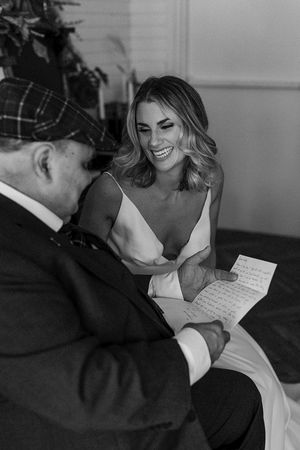 Black and white emotional moment of couple reading personal letters before ceremony.