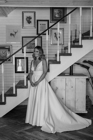 A white wedding gown flows elegantly against wooden stairs decorated with framed artwork.