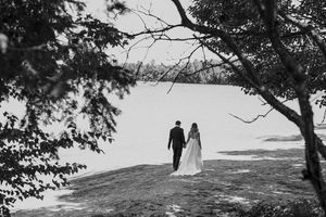 Black and white silhouettes of couple walking through trees in romantic wedding photo.