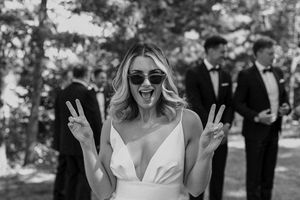 Joyful bride in sunglasses celebrating outdoors during wedding photoshoot.