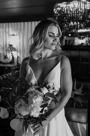 Dramatic black and white photos of bride with bouquet under crystal chandelier lighting.