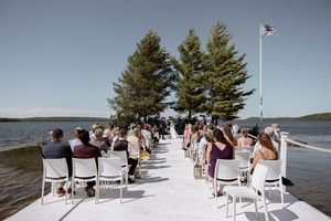 Wedding ceremony setup with white chairs on snowy beach overlooking water.