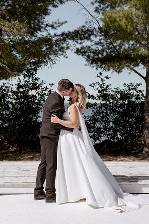 A tender moment captured during a waterfront wedding with a bride in a flowing white gown.