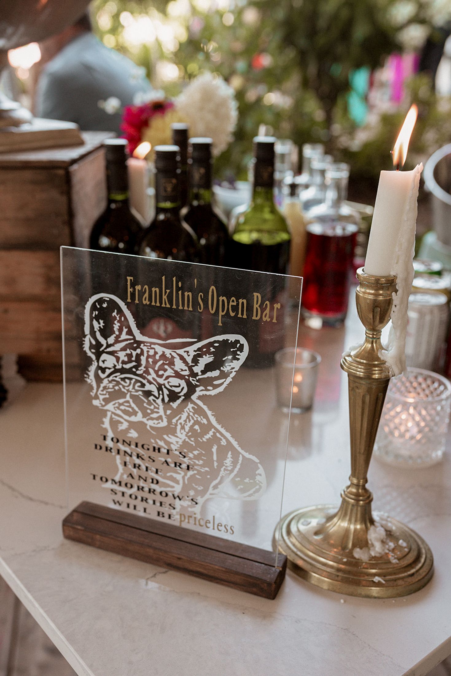 Elegant brass candlestick holders and decorative signs for Franklin's Open Bar displayed on white tablecloth settings.