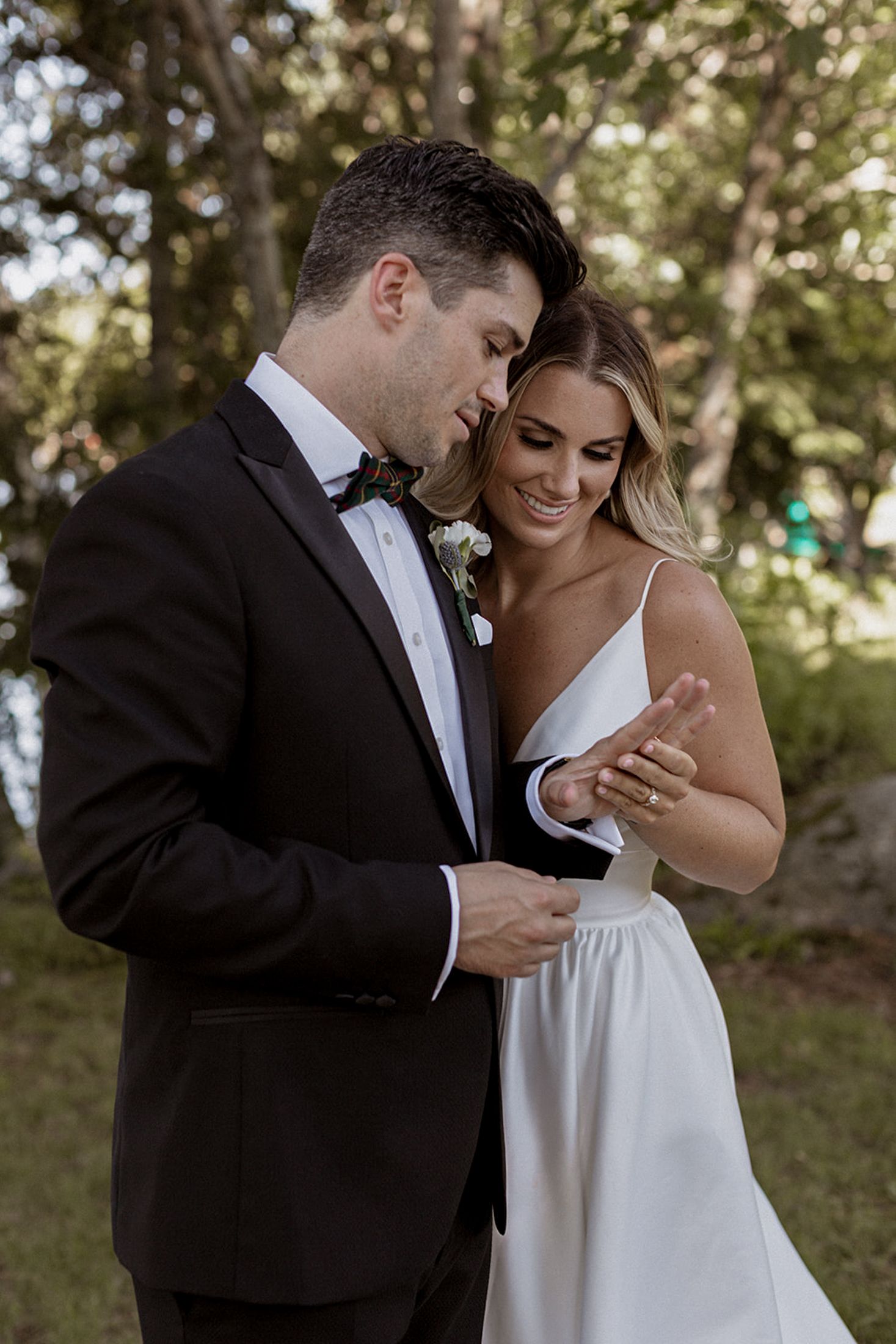 A couple in wedding attire share an intimate moment while dancing together outdoors in a natural setting.