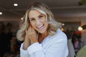 A radiant bride in white laughs candidly during wedding preparations.