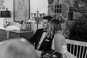 Black and white wedding reception scene with elegant candelabras and stone wall decor.
