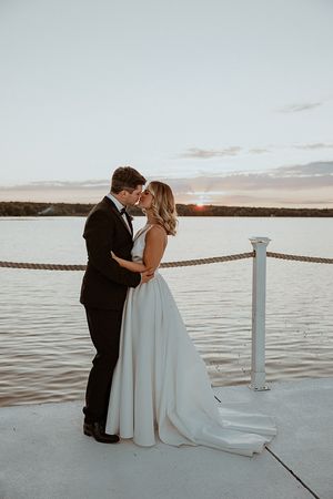Couple shares romantic moments on a waterfront deck during sunset.