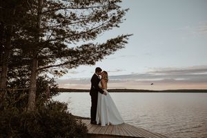 Scenic lakeside wedding photos with silhouettes against sunset sky.