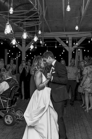 Black and white reception dance scene with hanging lights and flowing white dress.