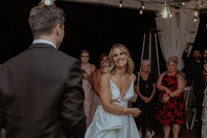 A joyful couple shares a dance moment at their wedding reception while guests look on and smile.