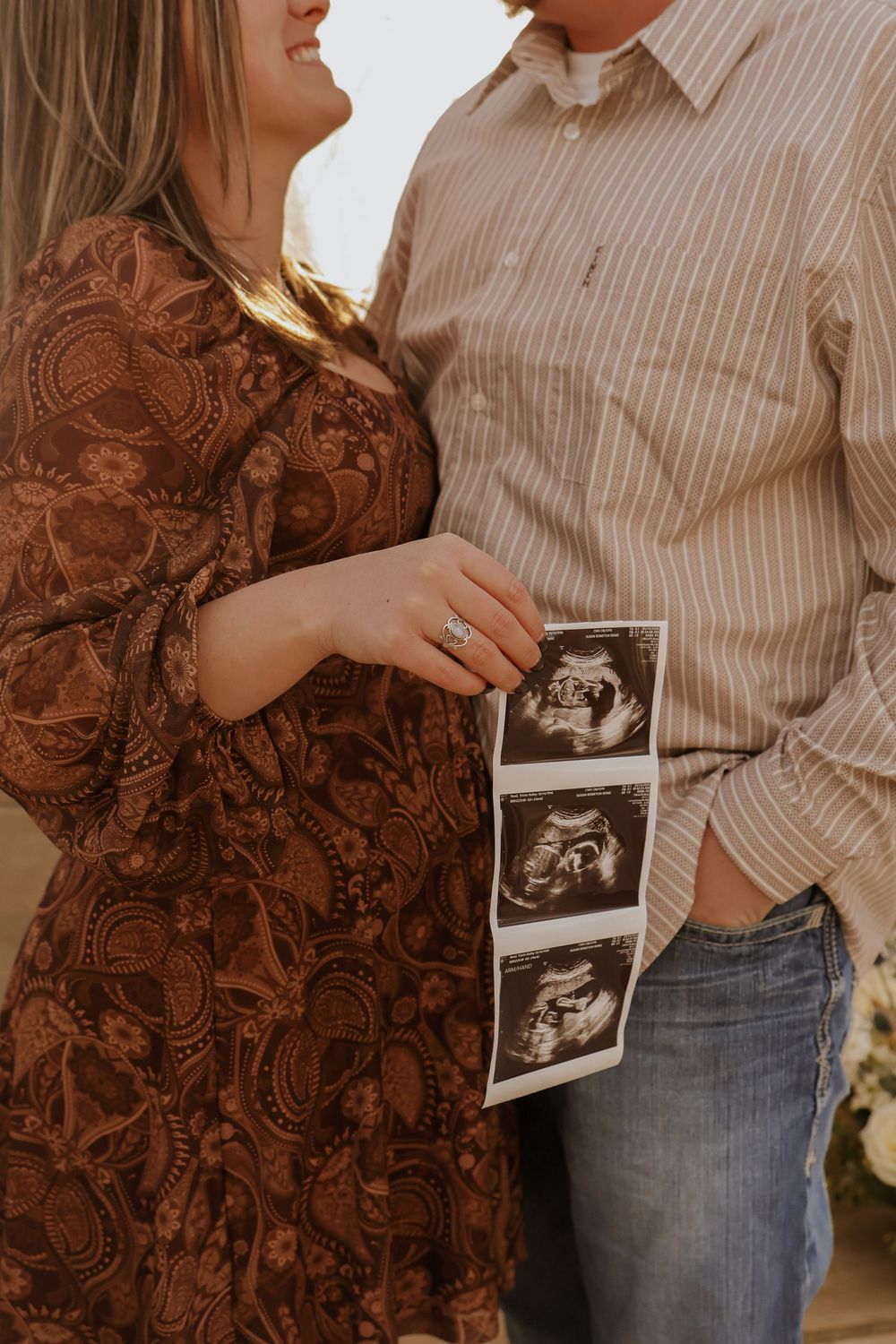 Couple holding ultrasound photos during pregnancy announcement session.