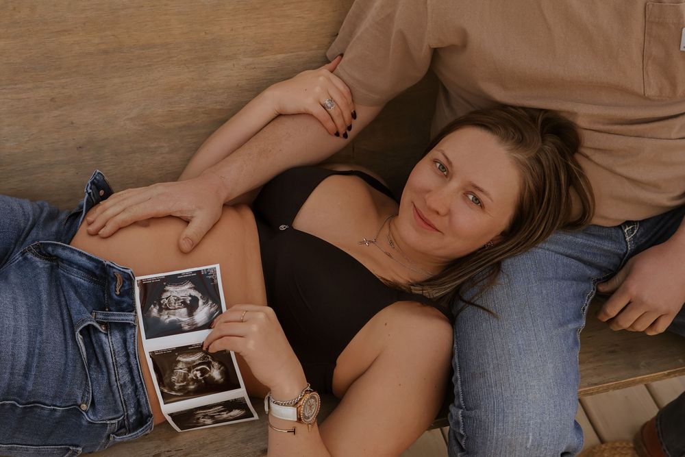 Pregnancy announcement photo with ultrasound images on denim.