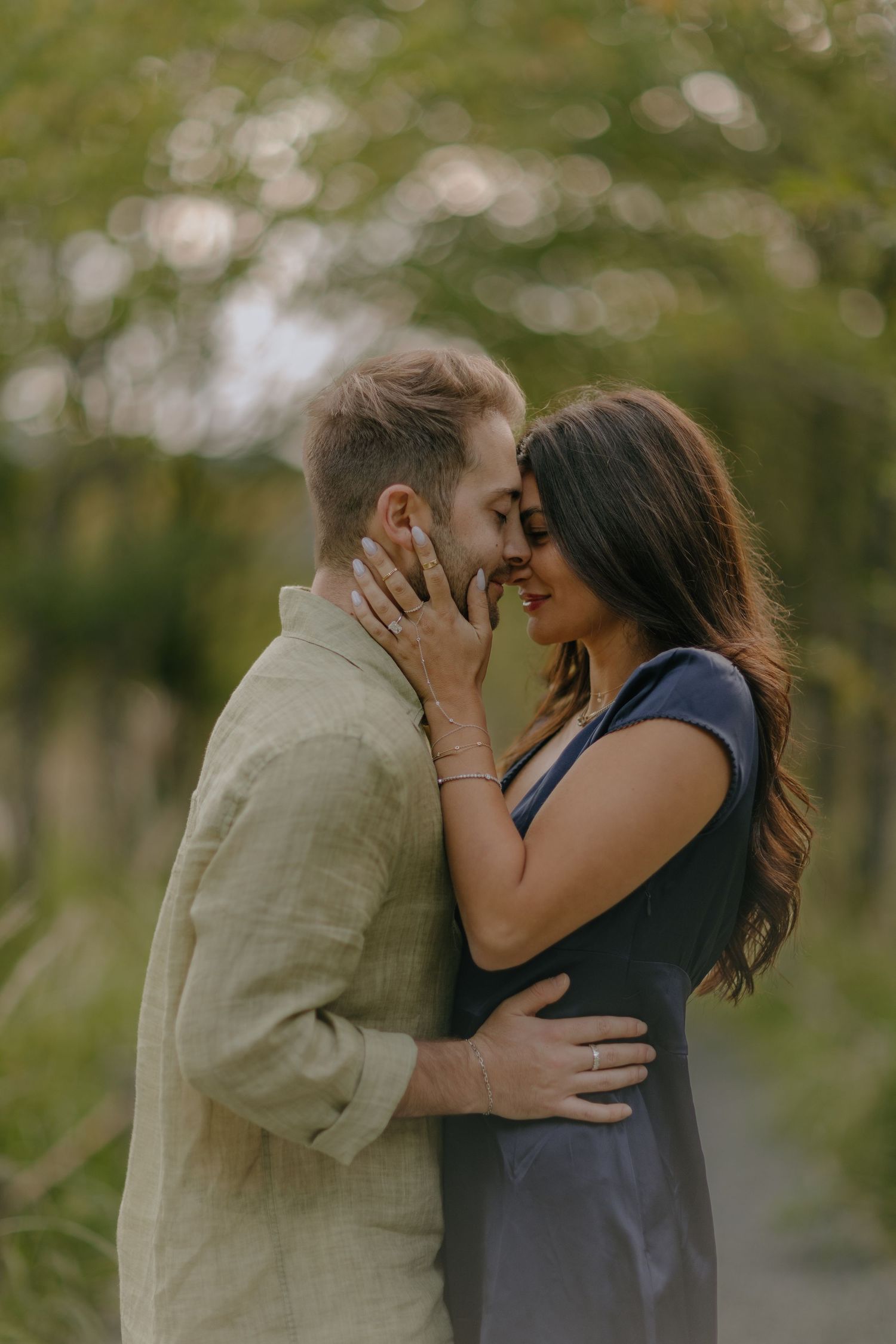 A couple shares an intimate kiss in a romantic outdoor setting with soft natural lighting and blurred trees in background in Hakone Japan